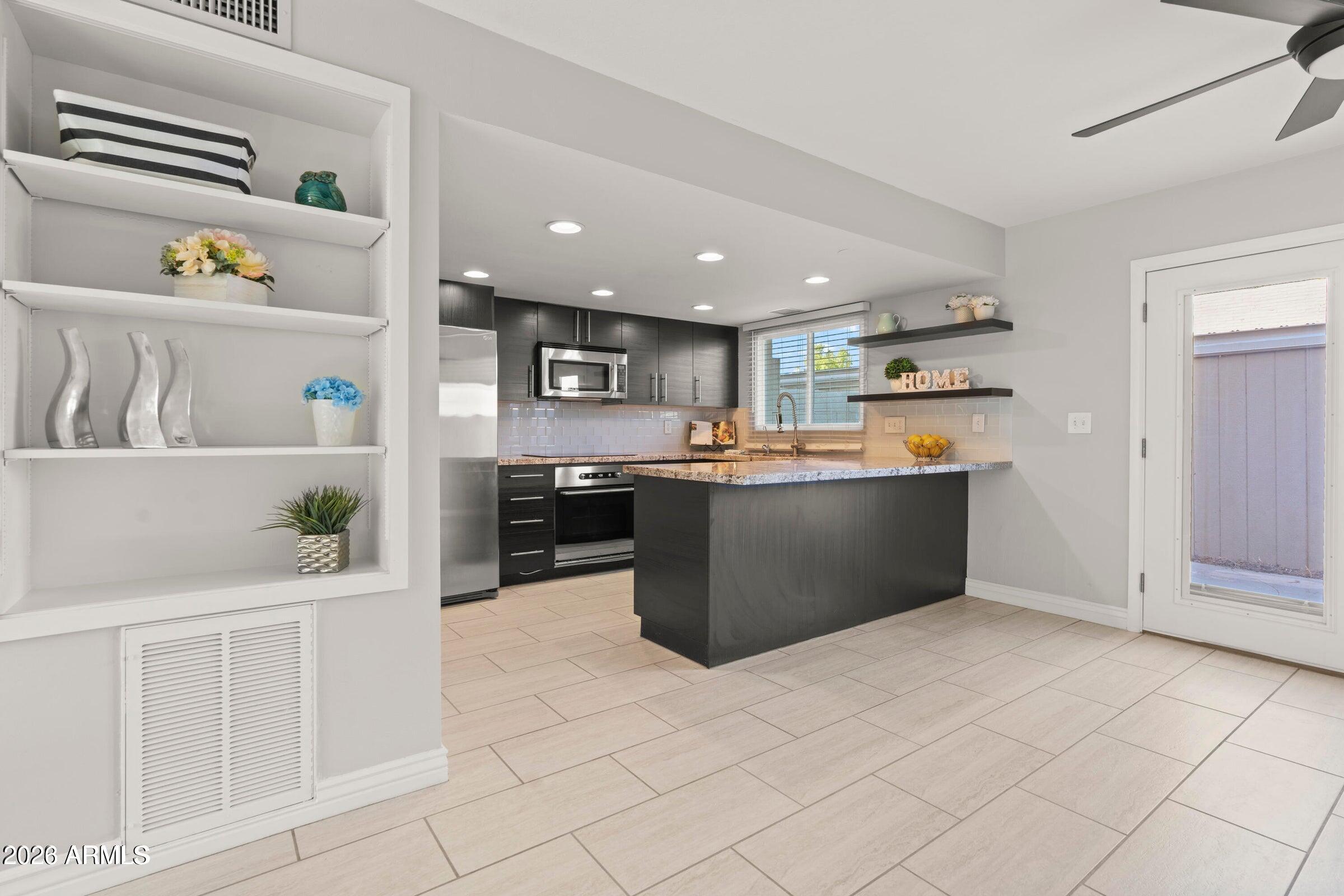 a kitchen with stainless steel appliances kitchen island granite countertop a refrigerator and a sink