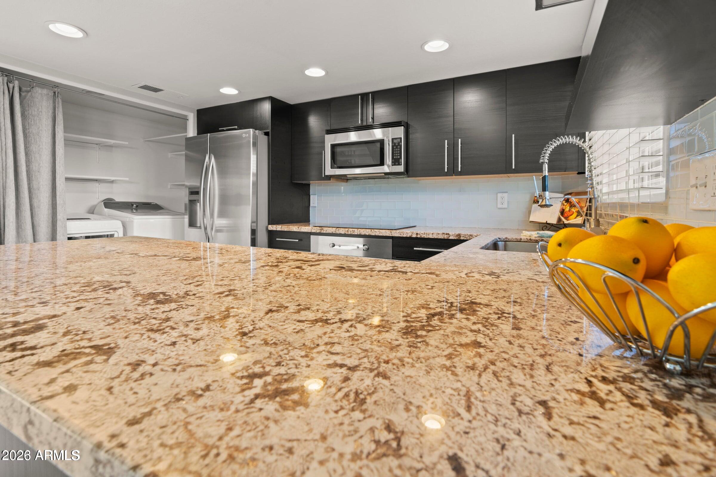 6909 East Osborn Road, Unit A Scottsdale, AZ 85251 - Photo 24 of 33 a large kitchen with stainless steel appliances kitchen island granite countertop a sink and cabinets