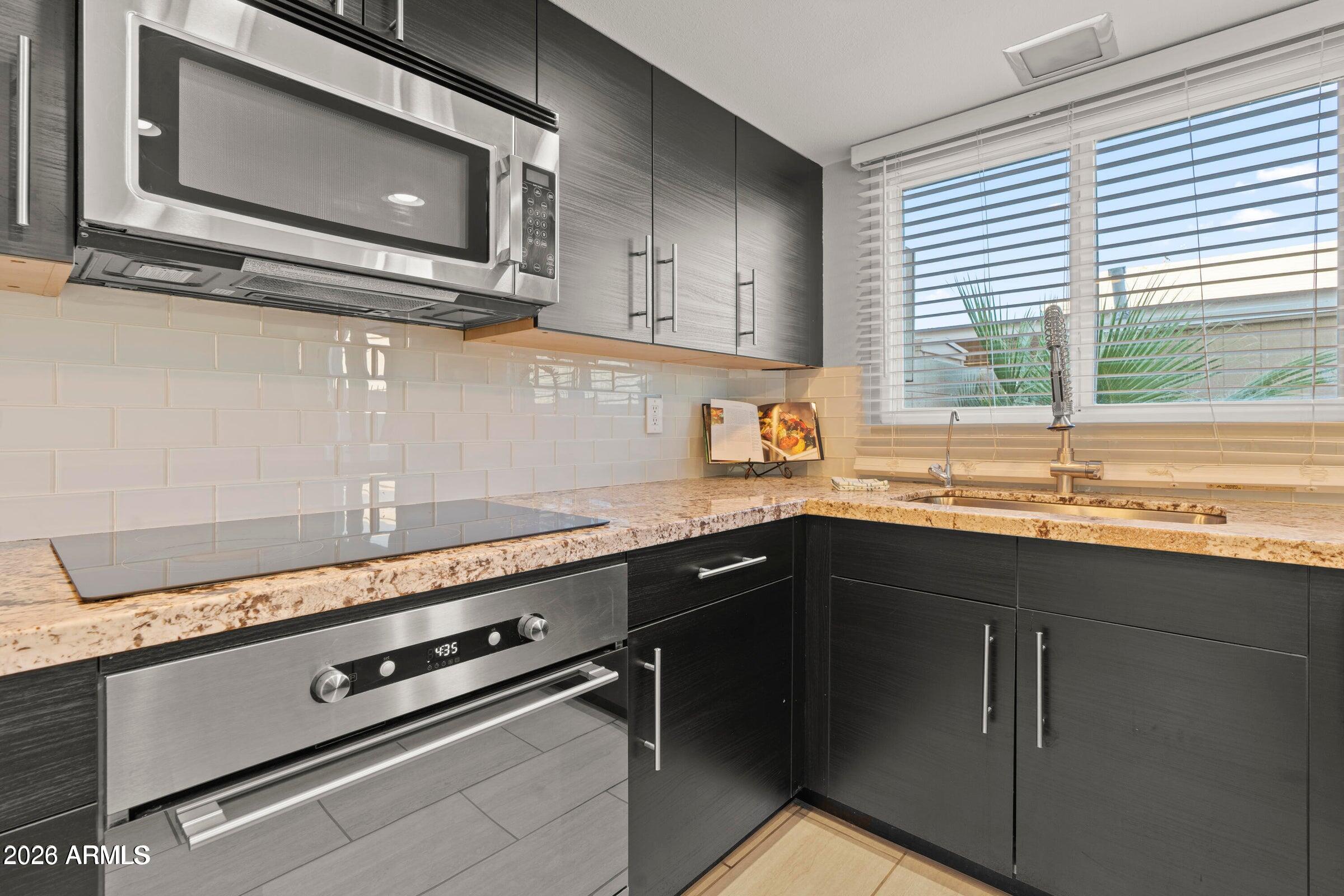 6909 East Osborn Road, Unit A Scottsdale, AZ 85251 - Photo 5 of 33 a kitchen with granite countertop a sink cabinets and window