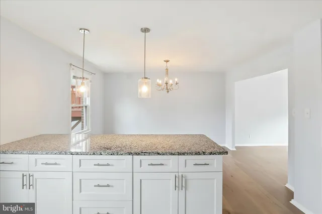 a kitchen with granite countertop white cabinets and a wooden floor