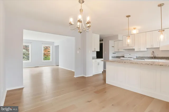 a view of a kitchen with granite countertop cabinets a sink a dining table and appliances