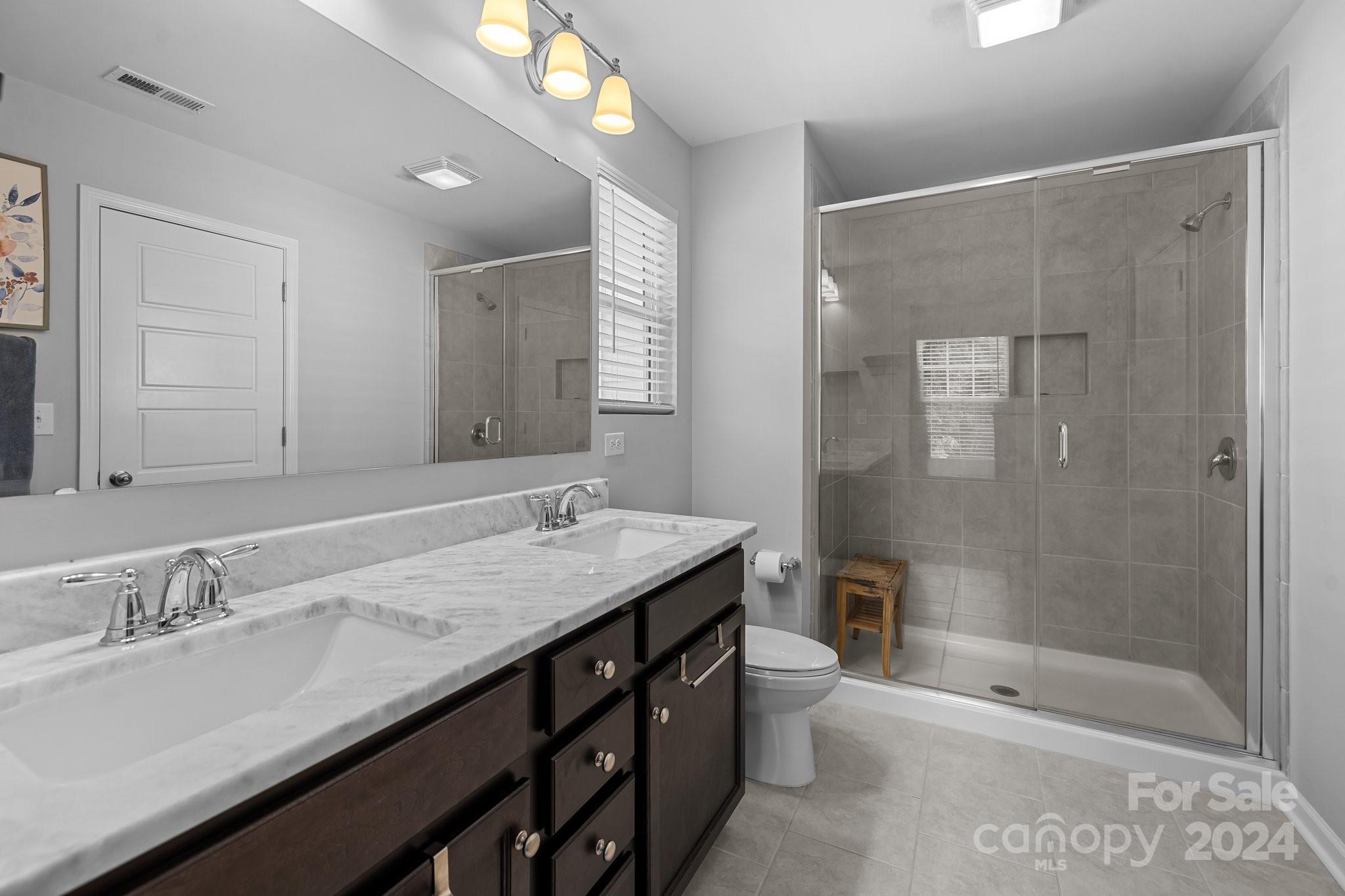 1152 Streamside Lane York, SC 29745 - Photo 29 of 47 a bathroom with a granite countertop sink a toilet a shower and a mirror