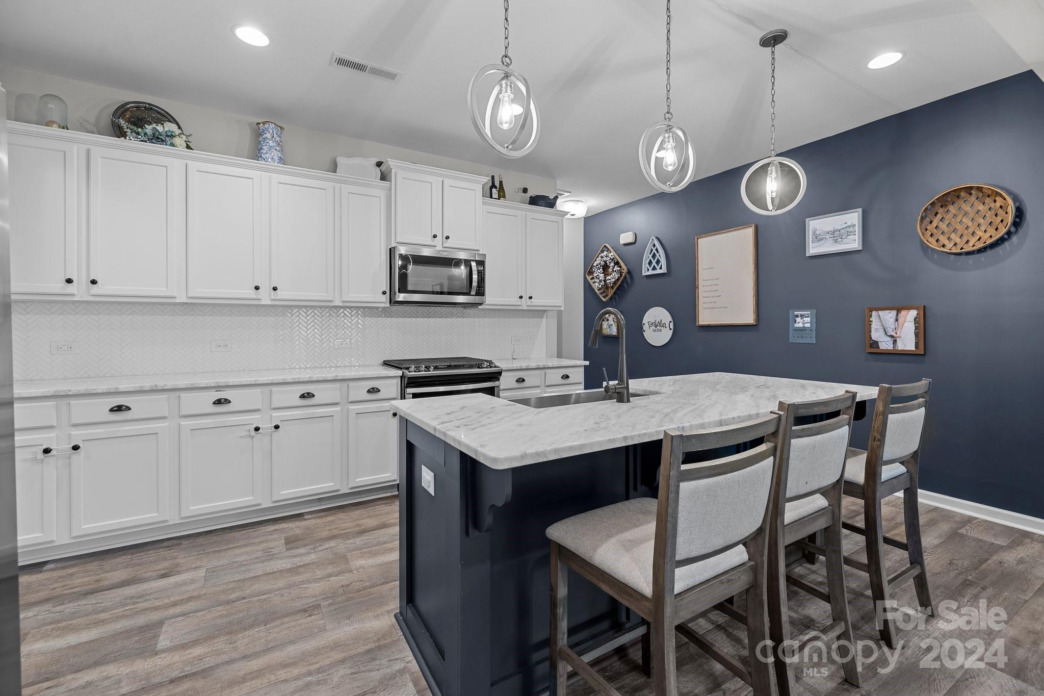 1152 Streamside Lane York, SC 29745 - Photo 7 of 47 a kitchen with stainless steel appliances granite countertop a stove a refrigerator a white table and chairs with wooden floor