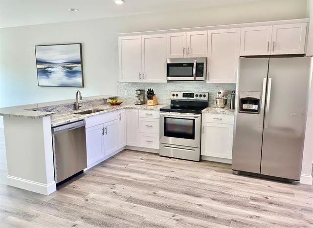 a kitchen with stainless steel appliances granite countertop a stove a sink and a refrigerator