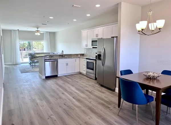a kitchen with granite countertop a table chairs stove and refrigerator