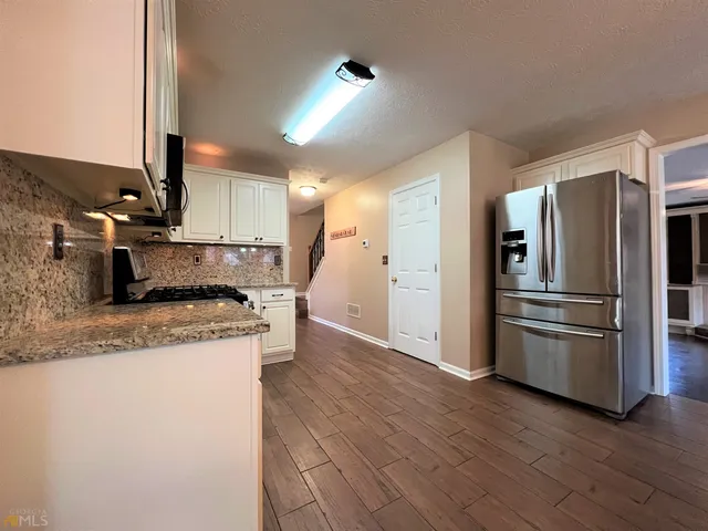 a kitchen with stainless steel appliances granite countertop a refrigerator a sink and a stove