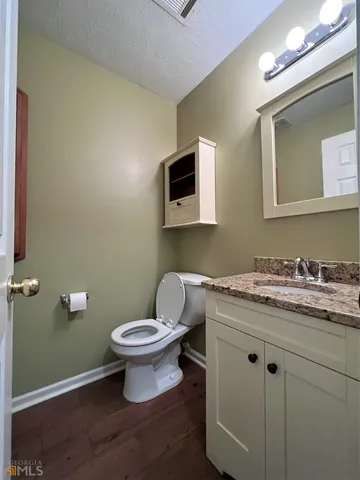 a bathroom with a granite countertop toilet a sink and mirror