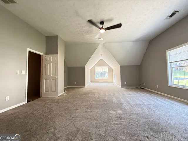 an empty room with windows and ceiling fan