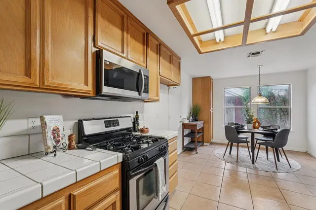 a kitchen with a stove and a dining table with granite countertop wooden cabinets
