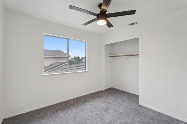 an empty room with a window and a fan