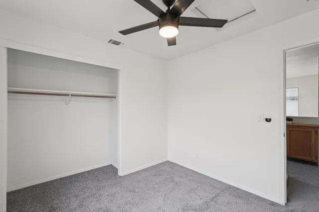 an empty room with closet and a chandelier fan