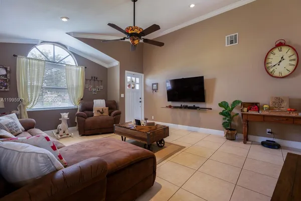 a living room with furniture a ceiling fan and a flat screen tv