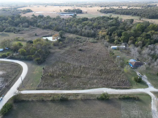 an aerial view of residential houses with outdoor space and trees