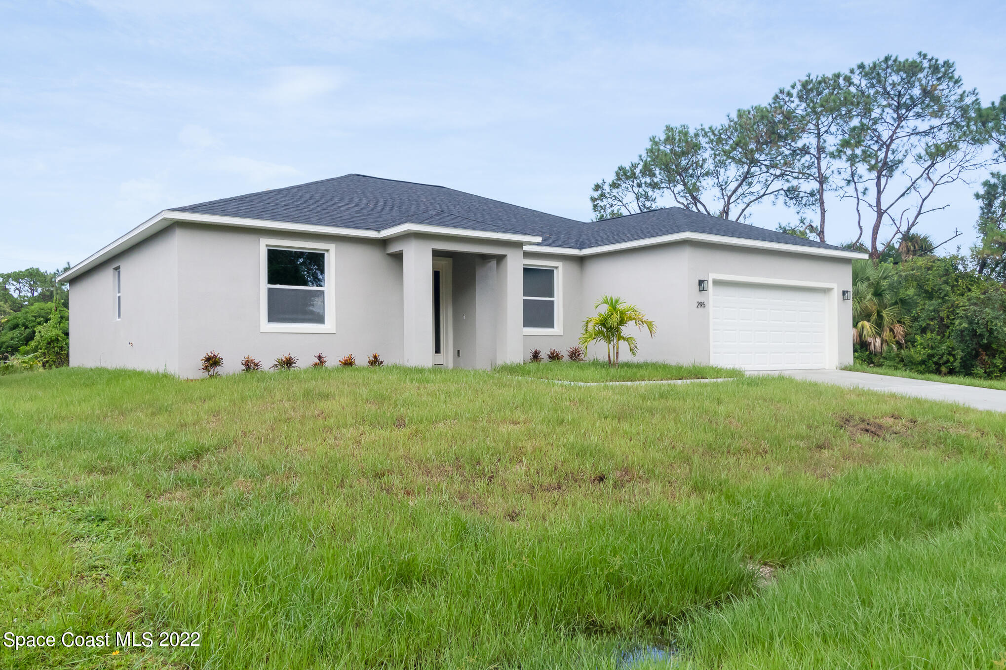 295 San Marino Road Southwest Palm Bay, FL 32908 - Photo 2 of 49 a view of a white house with a yard and plants