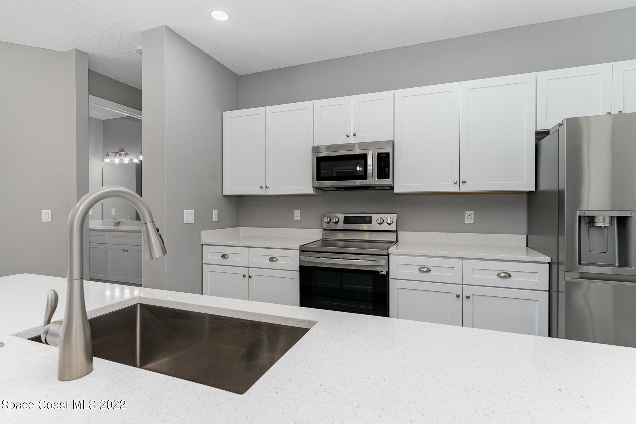 295 San Marino Road Southwest Palm Bay, FL 32908 - Photo 32 of 49 a kitchen with stainless steel appliances a stove microwave and cabinets