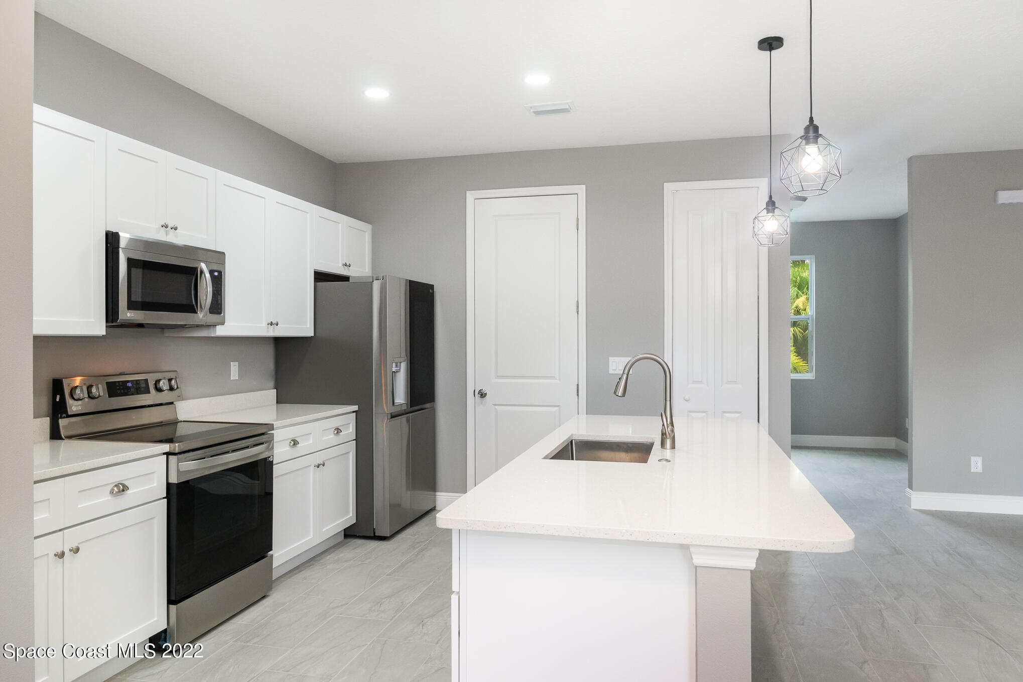 295 San Marino Road Southwest Palm Bay, FL 32908 - Photo 5 of 49 a kitchen with stainless steel appliances a stove refrigerator sink and microwave