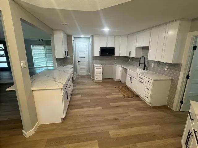 a large kitchen with stainless steel appliances granite countertop a sink a stove a refrigerator a microwave and cabinets