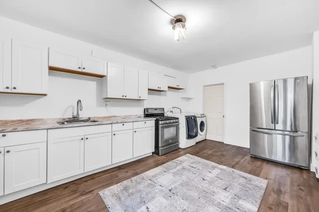 a kitchen with granite countertop a refrigerator stove top oven and sink