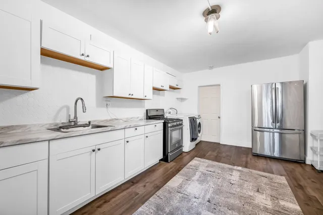 a kitchen with sink a refrigerator and white cabinets