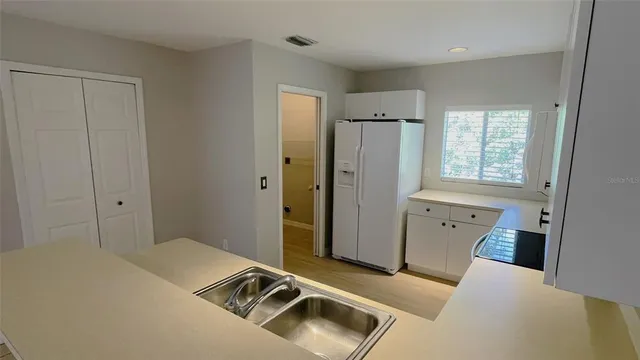 a kitchen with stainless steel appliances a refrigerator sink and white cabinets