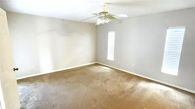 an empty room with windows and chandelier fan