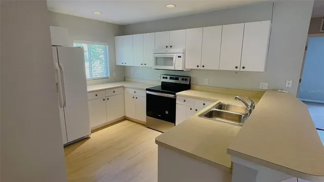 a kitchen with granite countertop white cabinets and white appliances
