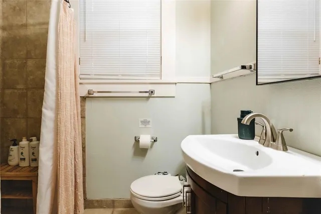 a bathroom with a sink a toilet and shower curtain