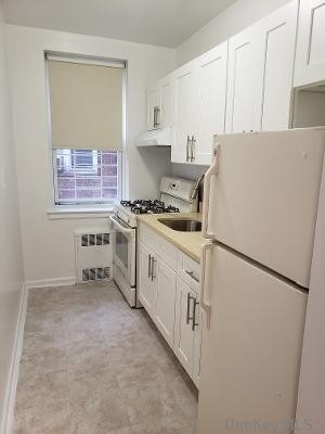a kitchen with cabinets appliances a sink and a refrigerator