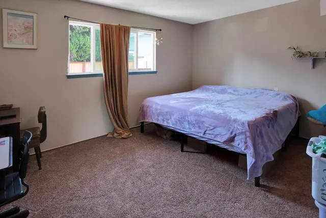 a spacious bedroom with a bed chair and a window