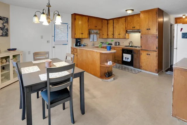 a kitchen with kitchen island a dining table chairs stainless steel appliances and cabinets