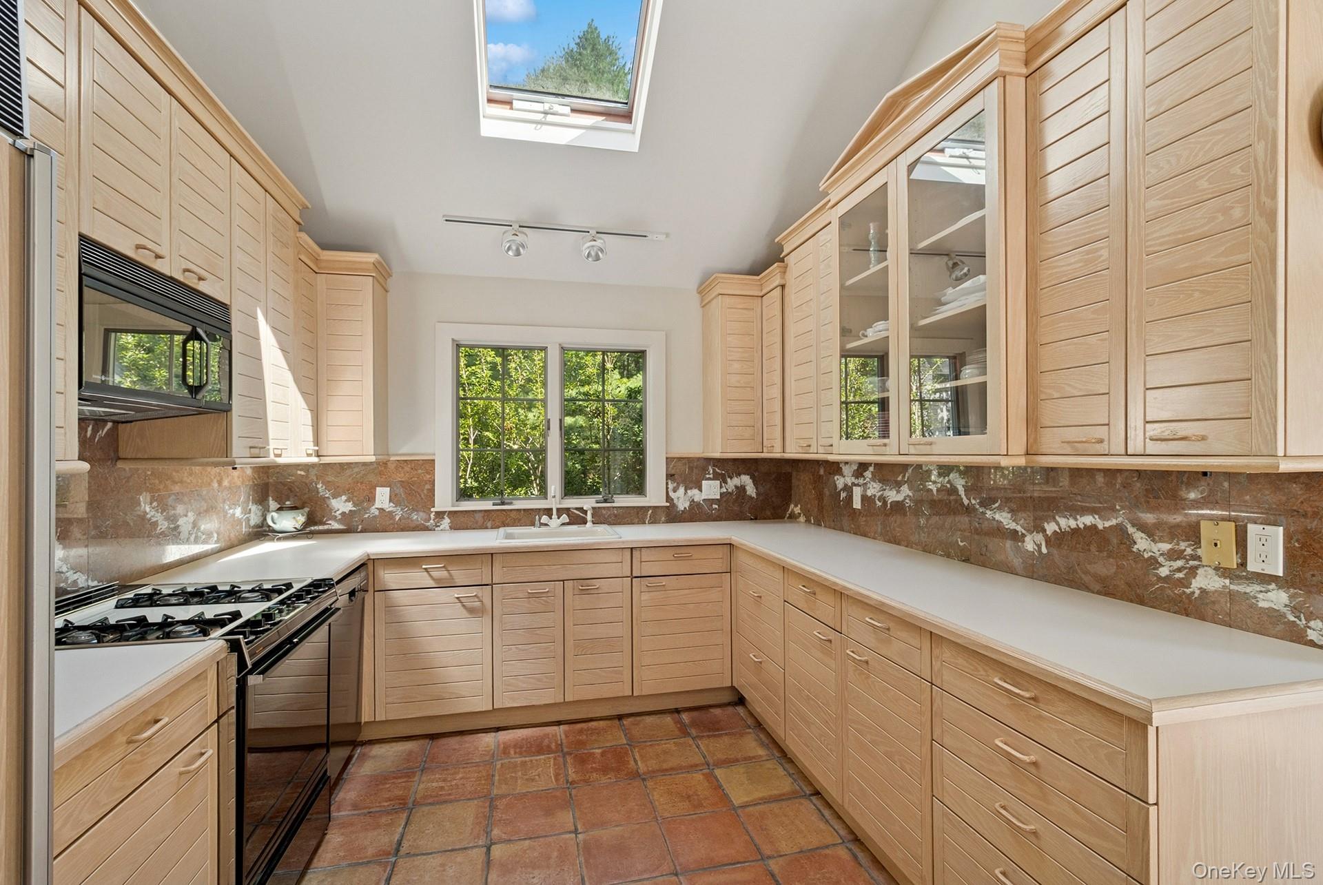 530 Hands Creek Road East Hampton, NY 11937 - Photo 17 of 47 Kitchen with light brown cabinets, black appliances, a skylight, backsplash, and lofted ceiling