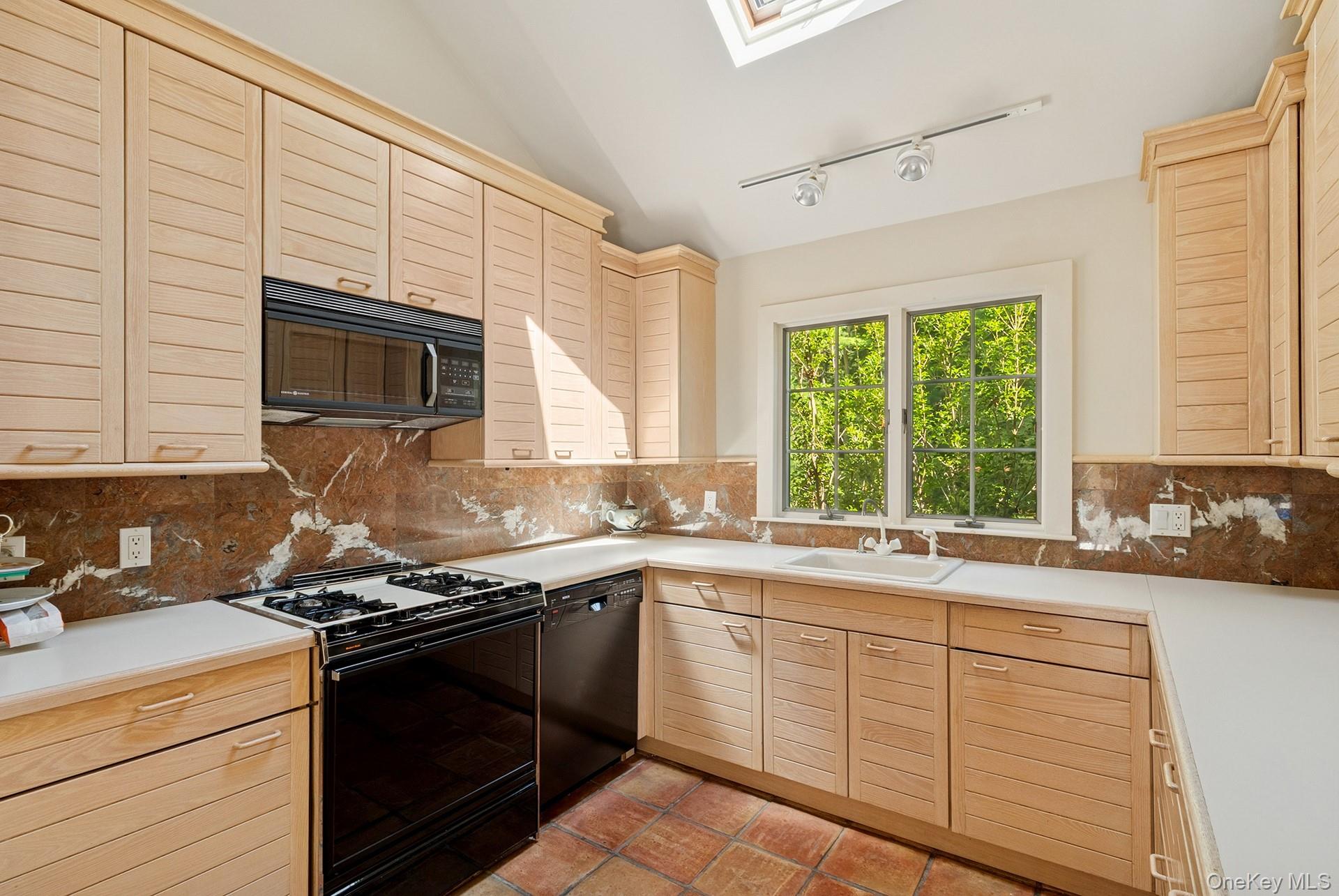 530 Hands Creek Road East Hampton, NY 11937 - Photo 18 of 47 Kitchen featuring black appliances, light brown cabinetry, a skylight, lofted ceiling, and tile patterned floors
