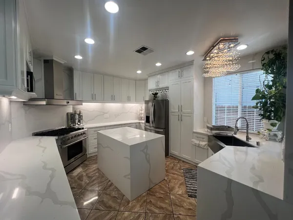 a kitchen with stainless steel appliances granite countertop a sink a stove and a refrigerator