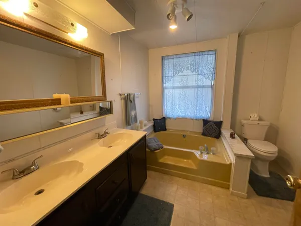 a bathroom with a tub sink toilet and mirror