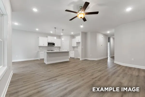 a view of an empty room with kitchen appliances and a ceiling fan