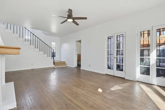 a view of an empty room with wooden floor and a ceiling fan