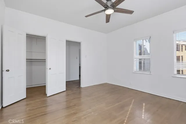 a view of an empty room with a window and wooden floor