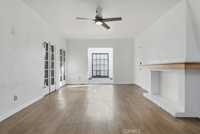 an empty room with wooden floor ceiling fan and windows