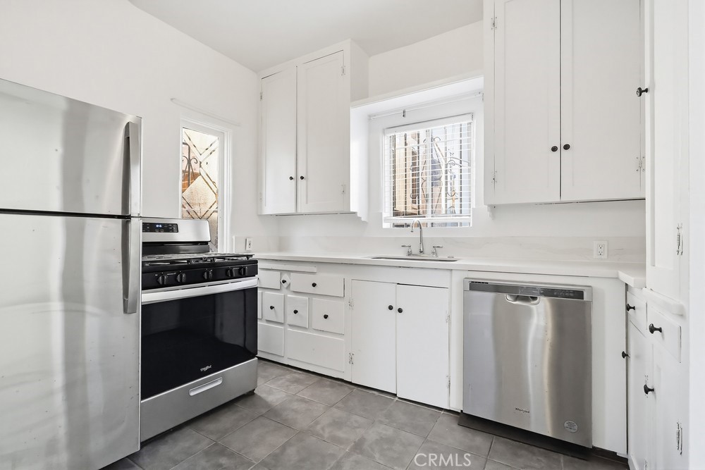 1527 East 3rd Street, Unit 1531 Long Beach, CA 90802 - Photo 9 of 38 a kitchen with granite countertop white cabinets white stainless steel appliances and sink