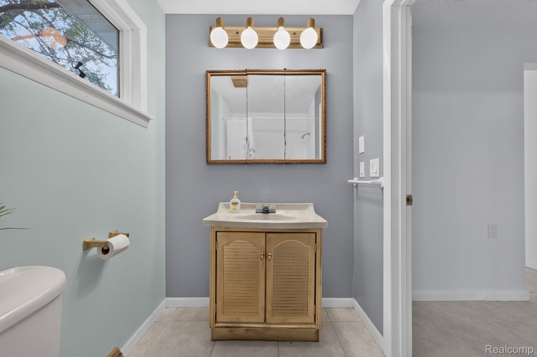 9288 Hilda Lane Flushing, MI 48433 - Photo 30 of 50 Bathroom featuring a wood-finish vanity with an integrated sink, a framed medicine cabinet, and a four-light vanity fixture