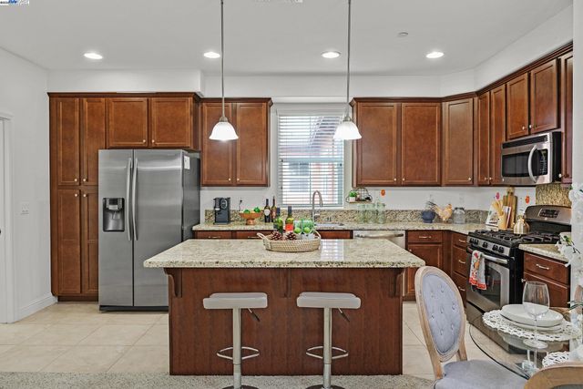a kitchen with stainless steel appliances granite countertop a sink a stove a refrigerator cabinets and chairs