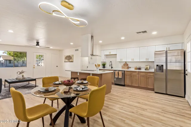 a kitchen with a dining table chairs wooden floor cabinets and stainless steel appliances