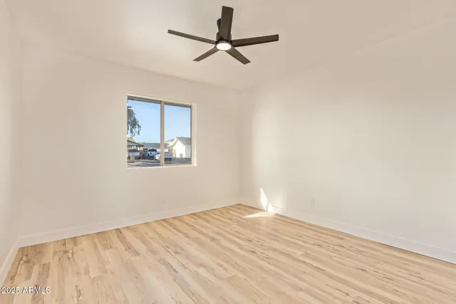 a view of empty room with wooden floor and fan