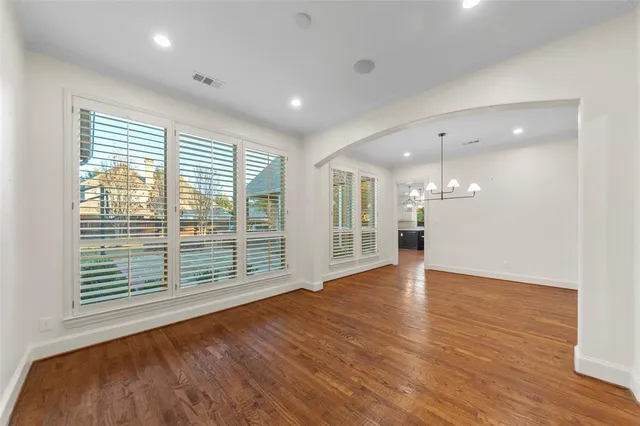 an empty room with wooden floor and kitchen view