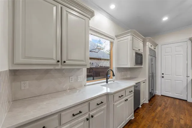 a kitchen with stainless steel appliances granite countertop a sink a stove and a wooden floor