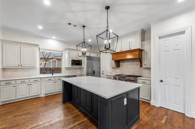 a kitchen with stainless steel appliances granite countertop a sink a stove and a wooden floors