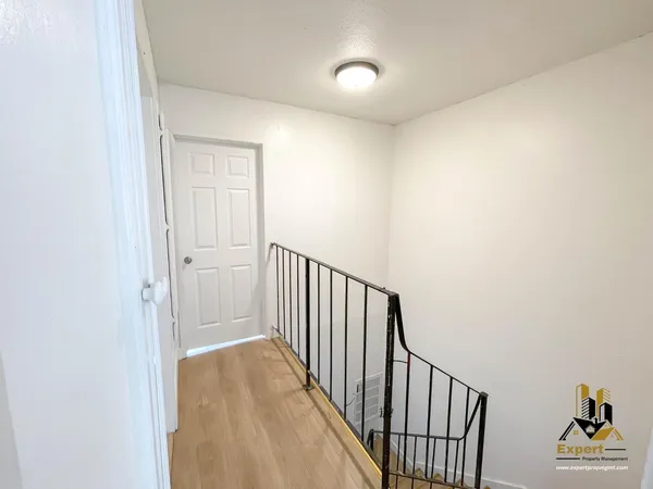 a view of a hallway with wooden floor and a bathroom