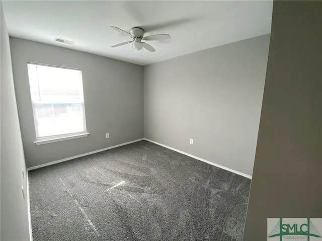 an empty room with a ceiling fan and carpet