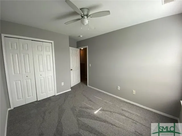an empty room with closet and a ceiling fan
