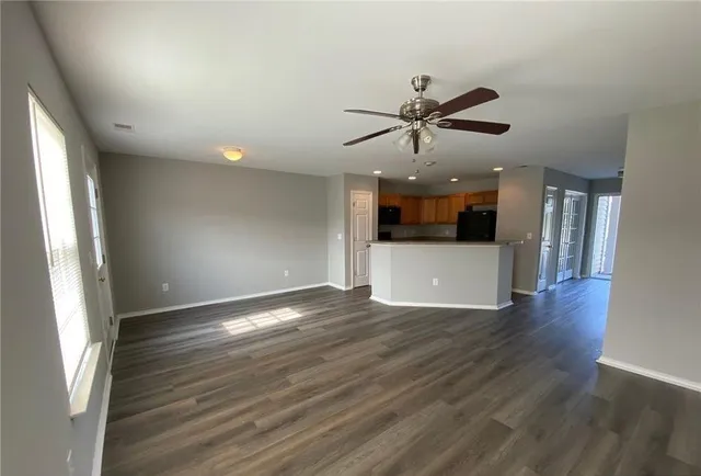 an empty room with wooden floor and a ceiling fan